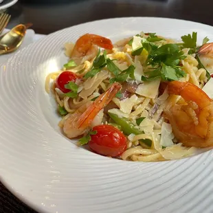 a plate of pasta with shrimp and tomatoes