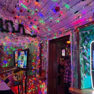 a man standing in a room with christmas lights on the ceiling