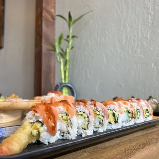a long plate of sushi with salmon and avocado