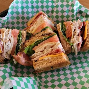 Traditional Club Sandwich with bacon, American and Swiss Cheese, ham, sliced turkey lettuce, tomatoes and mayo on Wheat