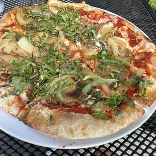 Regular pizza with chopped basil, sausage, and carmelized onions.