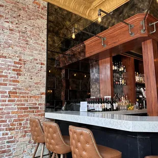 a bar with stools in front of a brick wall