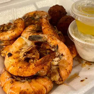 a tray of cooked shrimp with dipping sauce