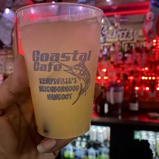 a person holding a drink in front of a bar