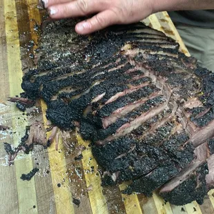 a person cutting a large piece of meat on a cutting board
