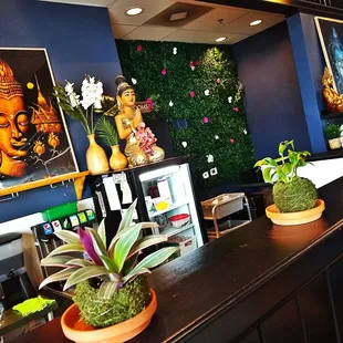 a bar area with plants and paintings on the wall