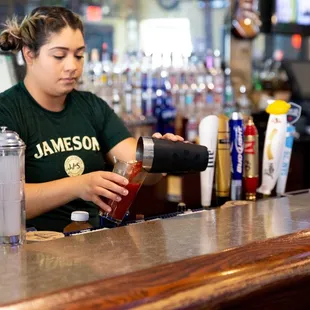 a woman pouring a drink at a bar