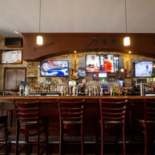 people sitting at a bar watching televisions