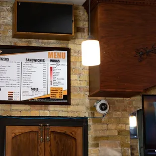 a television and a menu on a brick wall
