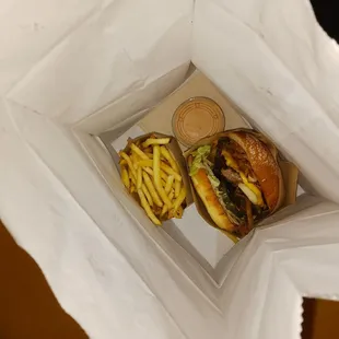 two burgers and fries in a paper bag