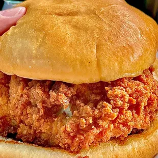 a hand holding a fried chicken sandwich