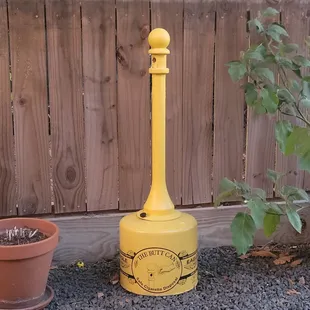 a yellow fire hydrant next to a potted plant