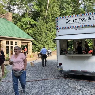 a man and woman walking past a food truck