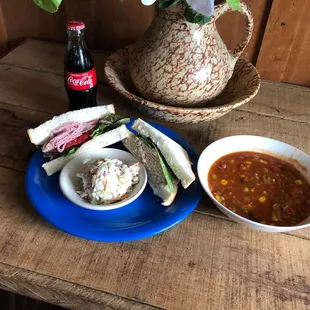 a table with soup, sandwiches, and a vase of flowers