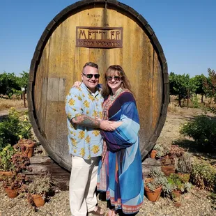 a couple standing in front of a barrel
