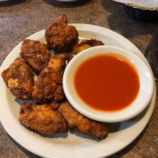 a plate of chicken wings and a bowl of sauce