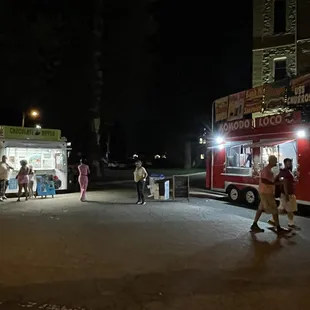 a food truck at night with people standing outside