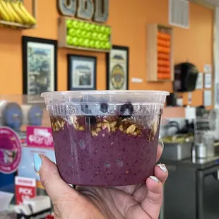 a hand holding a cup of blueberry smoothie