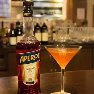 a bottle of aperol next to a glass of aperol