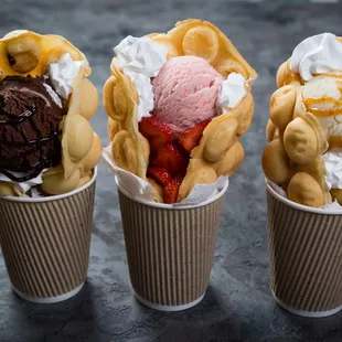 three ice cream sundaes in paper cups