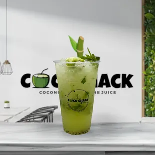 a glass of green drink on a counter