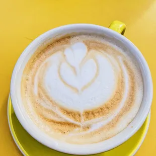 a cup of cappuccino on a yellow plate