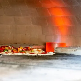 a pizza cooking in a brick oven