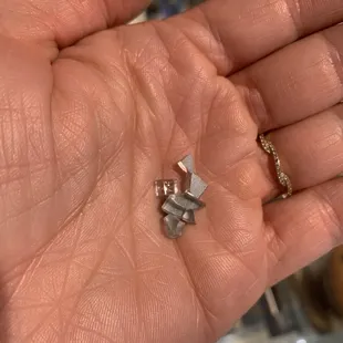 a person's hand holding a small crystal