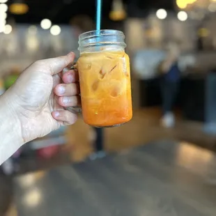 a hand holding a jar of iced tea
