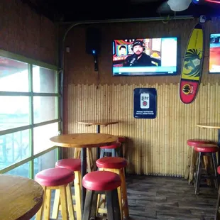 a bar with red stools and a television