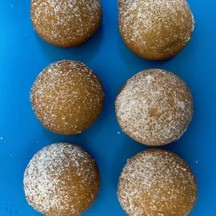 six sugar coated doughnuts on a blue plate