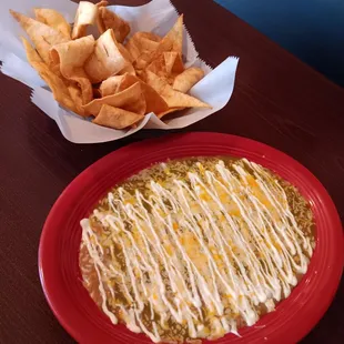 Bean dip with sour cream, cheese and green sauce. Flour chips on the side