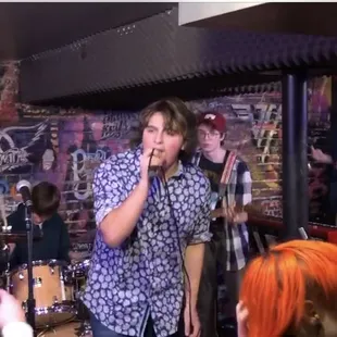a group of people singing in front of a brick wall