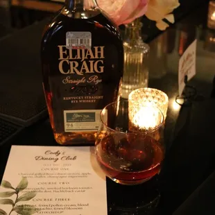 a glass of bourbon and a menu