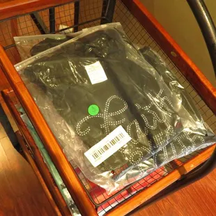 a table with a bag of black t - shirts