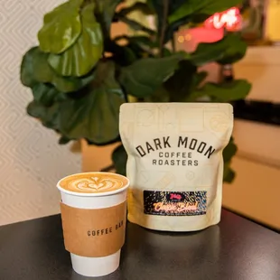a cup of coffee and a bag of dark moon roasters coffee