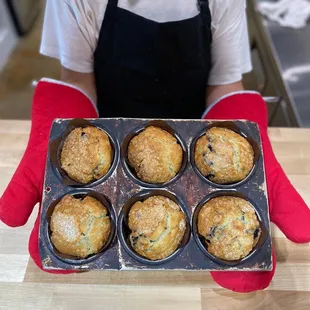 a person holding a tray of muffins