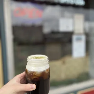 a hand holding a jar of iced coffee