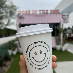 a hand holding a cup with a smiley face drawn on it