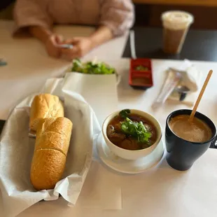 a woman sitting at a table with a sandwich and soup