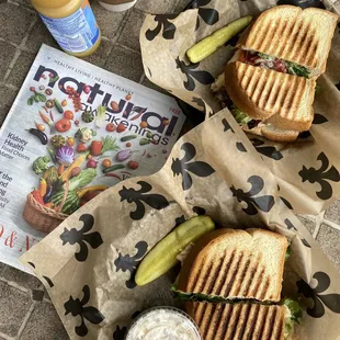 Italian chicken panini sandwiches with potato salad, pickles, orange juice, coffee and a copy of Natural Awakenings local health magazine.