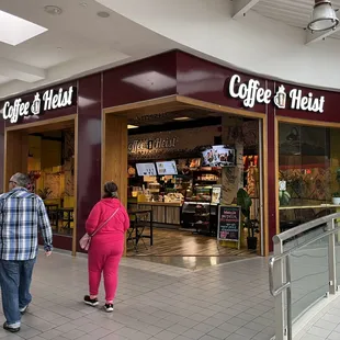 two people walking in front of a coffee shop