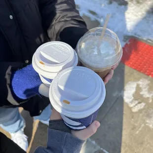 a person holding two cups of coffee