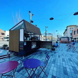 a view of a street with tables and chairs