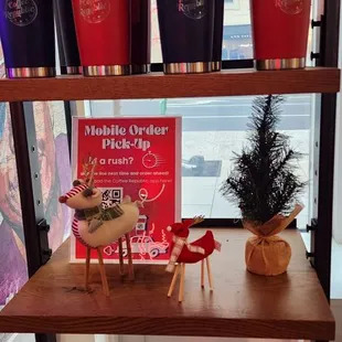 a shelf with coffee cups and a christmas tree