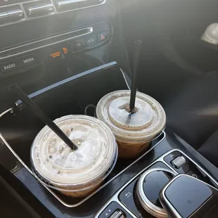 two cups of iced coffee in a car