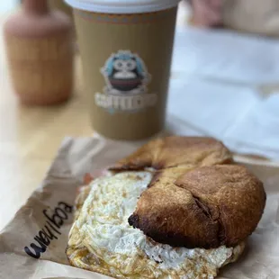 a croissant sandwich and a cup of coffee