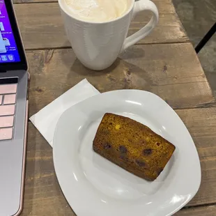 a piece of cake on a plate next to a cup of coffee