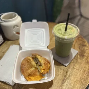 a croissant and a green smoothie on a table