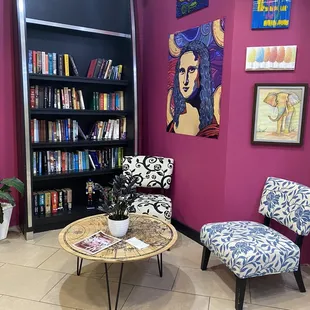 two chairs and a table in front of a bookshelf
